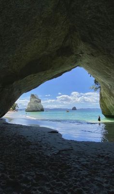 a person standing in the water under a cave