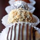 three chocolate covered desserts lined up on paper plates with crumbled toppings