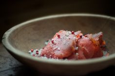 two pieces of meat in a wooden bowl with salt and pepper on the side,