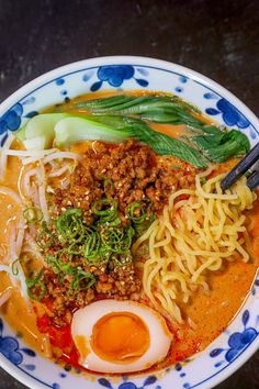 a bowl filled with noodles, meat and an egg