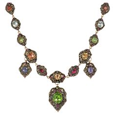 A highly important Georgian Swiss enamel, gold, and multi-gemstone necklace with pendant elements, in 18k. The elaborately decorated links are set with topaz, peridots, garnets, sapphires, emeralds, and rubies and feature scrolled foliate patterns on both sides. Necklace: 16.25" long, center including drop: 2.25" long Similar necklace pictured in "Understanding Jewellery" by David Bennett & Daniela Mascetti, page 81, plate 52 * Includes letter of authenticity * Free insured shipping * Please do