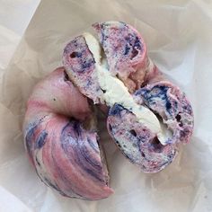 two doughnuts that are sitting on wax paper with blue and pink swirled icing