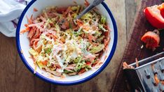 a bowl filled with coleslaw next to sliced tomatoes