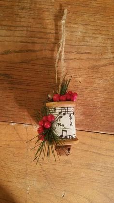 a planter with red flowers and musical notes hanging from it's side on a wooden surface