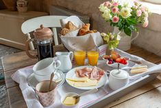 a breakfast tray with eggs, ham, fruit and juice