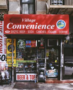 a store front with various signs on the side of it that read village convenience, exotic beer - soda - candles - cigars - coffee