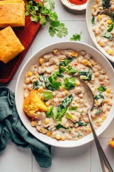 two bowls of white bean soup with corn and parsley on the side next to bread