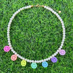 a necklace that has buttons on it in the middle of some grass with beads around it