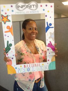 a woman is holding up a national papioli week photo frame in an office cubicle