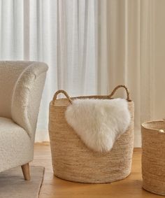 a white chair sitting next to a basket on top of a wooden floor in front of a window