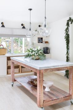 a kitchen island with marble top in front of a window and plants on the counter