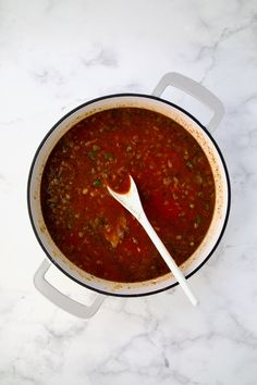 a bowl of soup with a spoon in it on a marble counter top, ready to be eaten