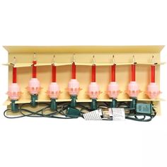 a wall mounted electrical device with six red candles on it's sides and wires running through the middle