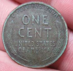 a close up of a coin in someone's hand with the word one cent printed on it