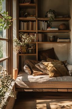 a bed sitting in front of a window next to a wooden shelf filled with books