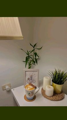 a table topped with a vase filled with flowers and candles next to a potted plant