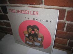 the shirelles - an anthology cd album on display in front of a brick wall