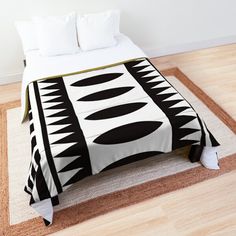 a black and white bed spread on top of a wooden floor next to a rug