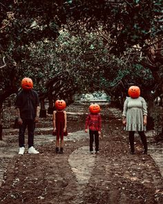 a group of people with pumpkin heads walking down a dirt road