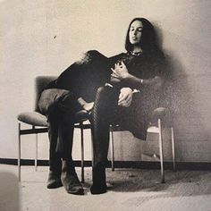 black and white photograph of two people sitting next to each other, one holding a cat