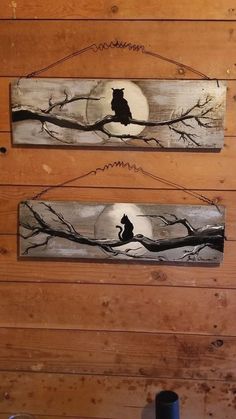 two wooden signs with cats on them hanging from the side of a wood paneled wall