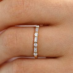 a woman's hand with a gold and white diamond ring on her left hand