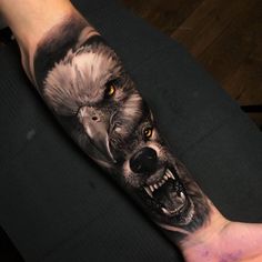 a man with a wolf and eagle tattoo on his arm that is painted in black and grey