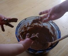 two hands reaching for chocolate in a bowl