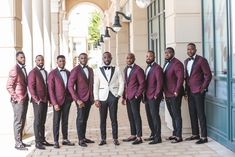 a group of men standing next to each other wearing suits and bow ties in front of a building