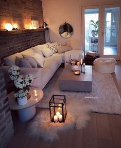 a living room with white furniture and candles on the coffee table in front of it