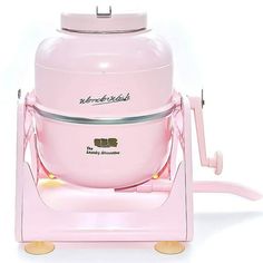 a pink ice cream maker sitting on top of a white table next to a cup