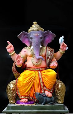 an elephant statue sitting on top of a table next to a black background with gold trimmings