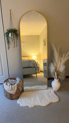 a mirror sitting on top of a carpet next to a vase with feathers in it