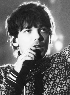 a black and white photo of a person with his hand on his chin looking at the camera