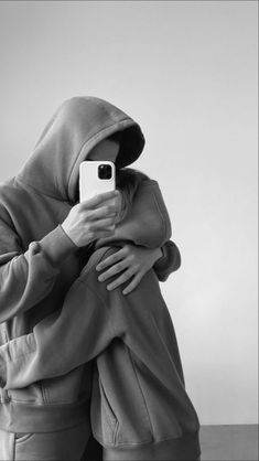 a person in a hoodie taking a selfie with their cell phone while wearing a sweatshirt