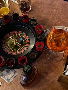 a table with glasses and a casino wheel clock on it, next to some drinks