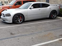 a silver car parked in a parking lot next to another red car and brick building