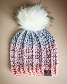 a knitted hat with a white and pink pom - pom on top