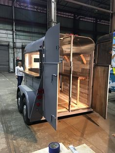 a man standing next to a truck in a warehouse with its doors open and shelves on the side