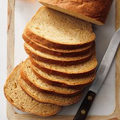 a loaf of bread sitting on top of a wooden cutting board next to a knife