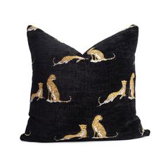 a black and gold pillow with cats on the front, sitting on top of it