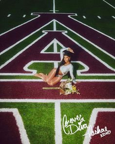 a woman laying on the ground in front of a football field with an arrow painted on it