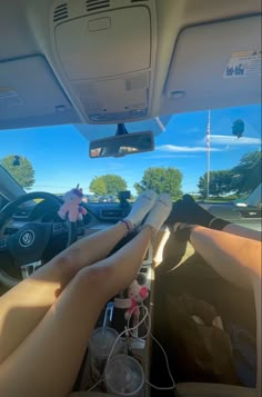 two people sitting in the driver's seat of a car with their feet on the steering wheel