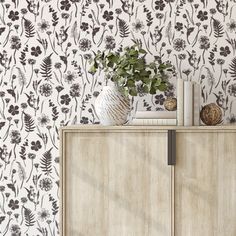 a white cabinet sitting next to a wall with black flowers on it's side