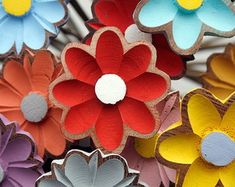 colorful paper flowers are arranged in rows on display