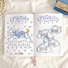 an open planner book on top of a bed with stars and clouds in the sky