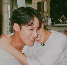 a young man is hugging his friend in the kitchen