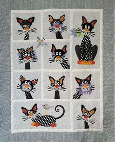 a quilted wall hanging with black and white cats on it