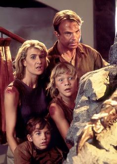 the family is posing for a photo in front of a large rock and some stairs