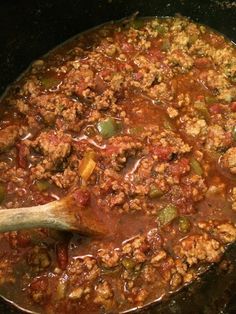 a pot filled with meat and vegetables cooking on top of a wooden spoon in it